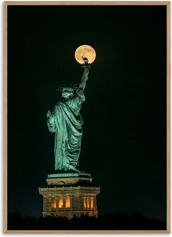 Statue of Liberty at night with a full moon perfectly aligned atop the torch, photo by Hua Zhu.