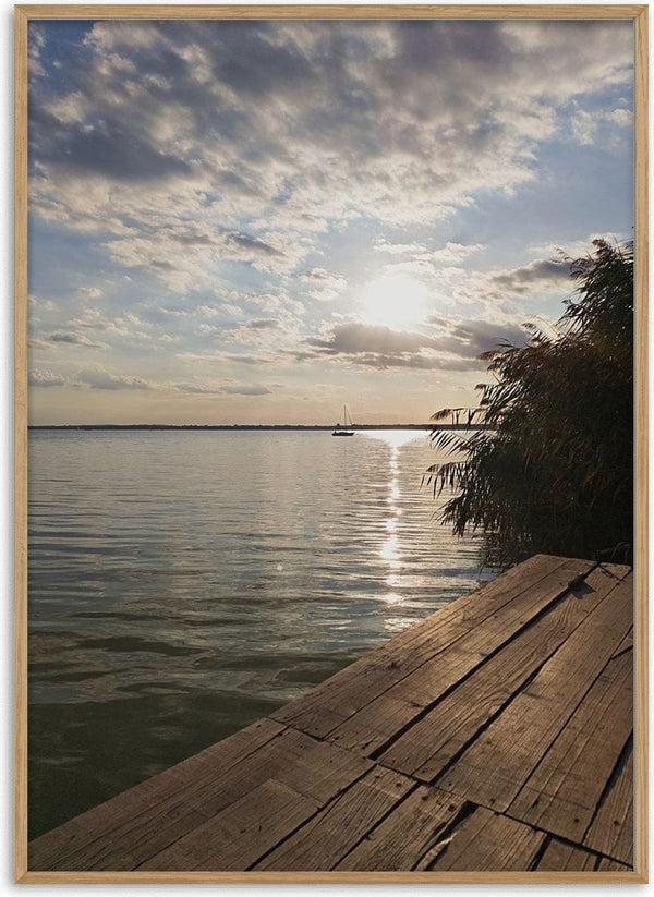 Sunset at the Lakeside Dock by Bora Kőhalmi - a wooden dock on Lake Balaton with a low sun and a silver path on the water